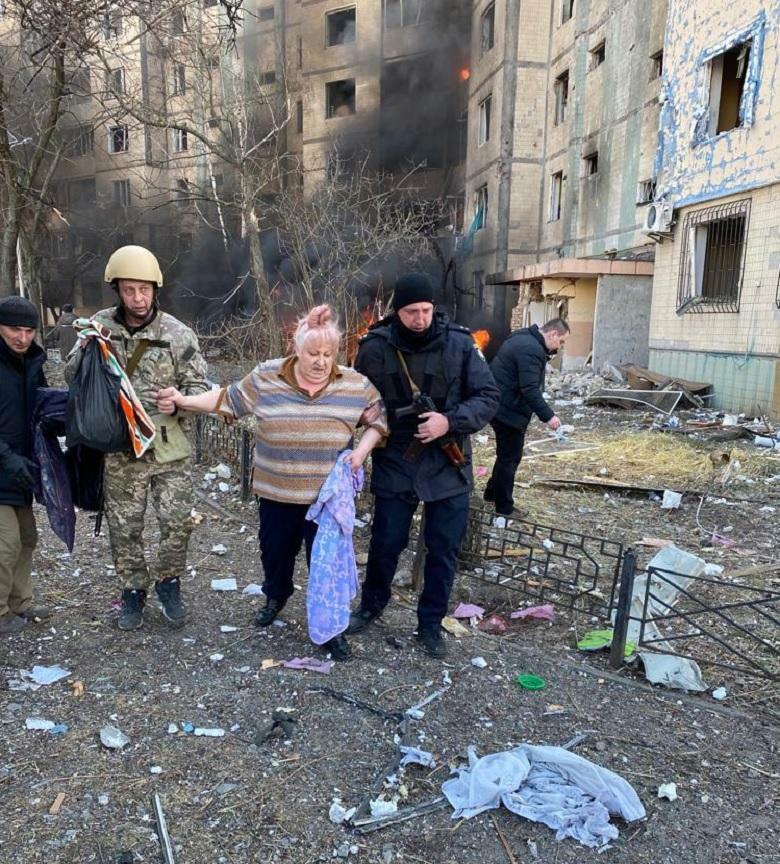 Archive photo of residents being assisted outside a damaged apartment building in Kyiv on 20 March 2022.